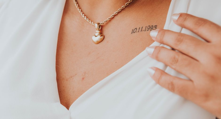 Elegant wedding guest wearing a fine gold pendant necklace at the collarbone, soft daylight, fine jewelry portrait