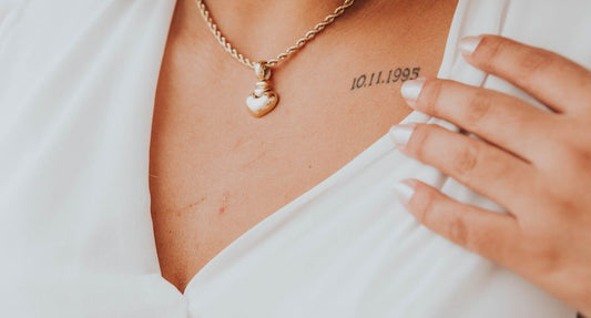 Elegant wedding guest wearing a fine gold pendant necklace at the collarbone, soft daylight, fine jewelry portrait