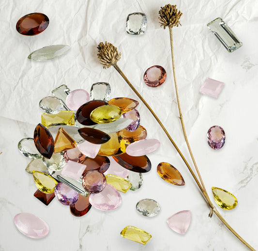 Vibrant assortment of colorful polished gemstones including amethyst, citrine, and jade arranged on a white marble surface