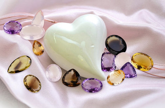 Assortment of loose faceted gemstones in varied colors arranged on a clean white surface, macro studio photography