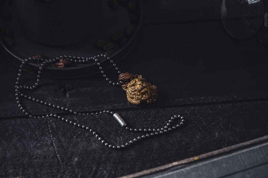 Gold lion-motif pendant necklace photographed in warm sunlight, close up on a neutral background