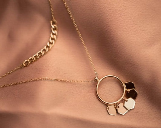 Solid 14K gold zodiac disc pendant necklace photographed close-up in natural light, fine jewelry detail