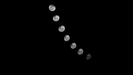 The eight phases of the moon cycle — from new moon to full moon — photographed against a dark night sky