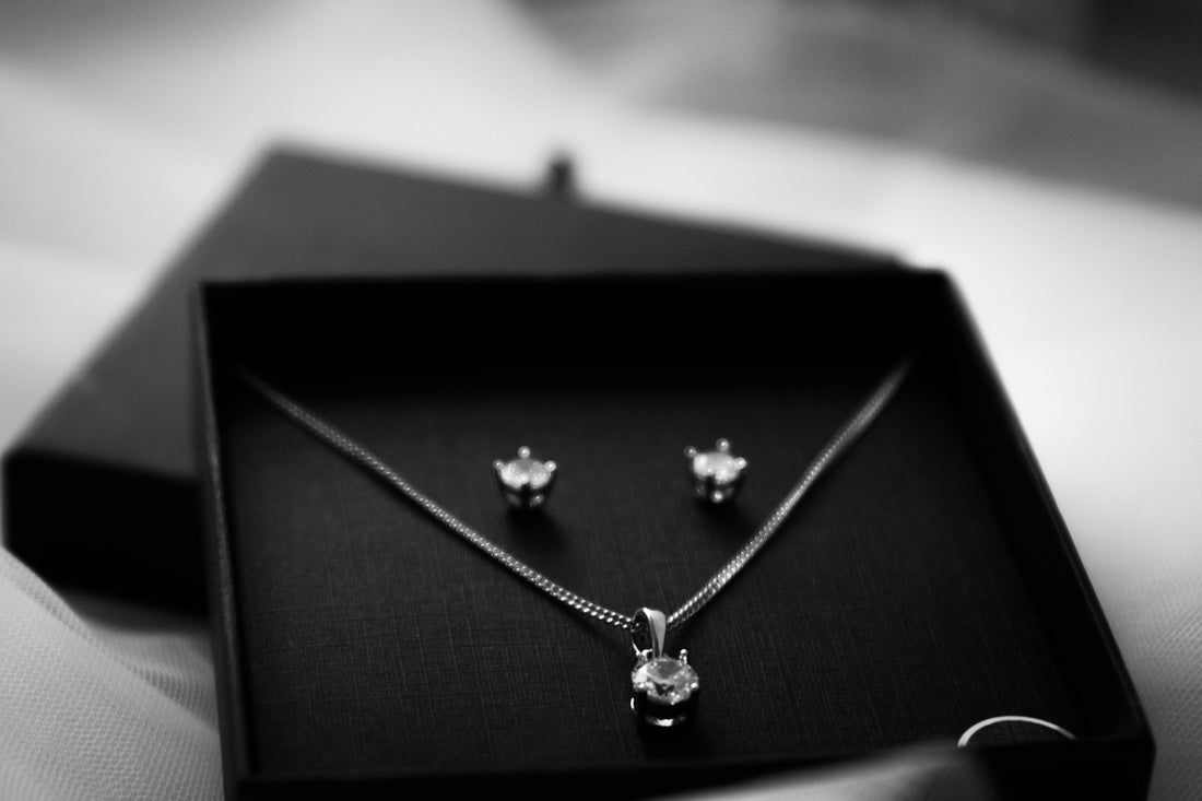Delicate sterling silver necklace and earrings set displayed in an open black gift jewelry box