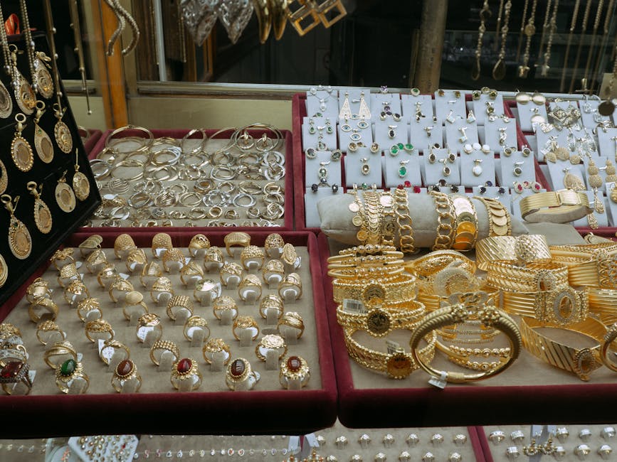 Assorted fine jewelry pieces in 14K yellow gold including rings, necklaces, and pendants arranged on white marble