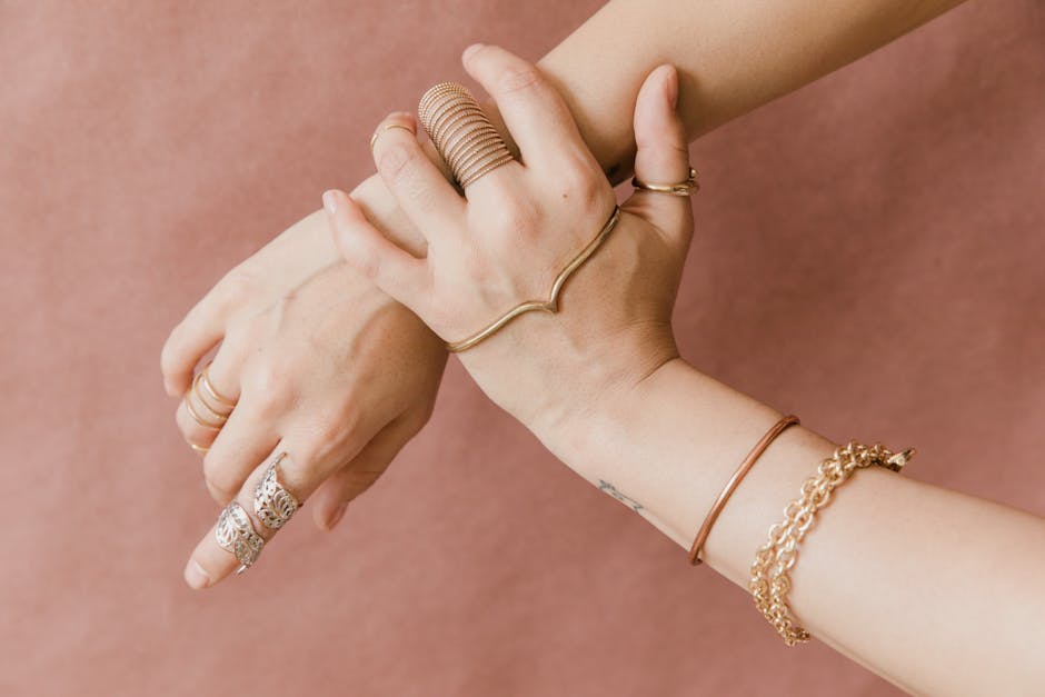 Stack of slim 14K gold birthstone rings worn on a hand in natural light, fine jewelry detail